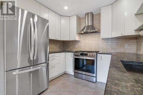 A modern kitchen with a stainless steel refrigerator and a stainless steel range hood.