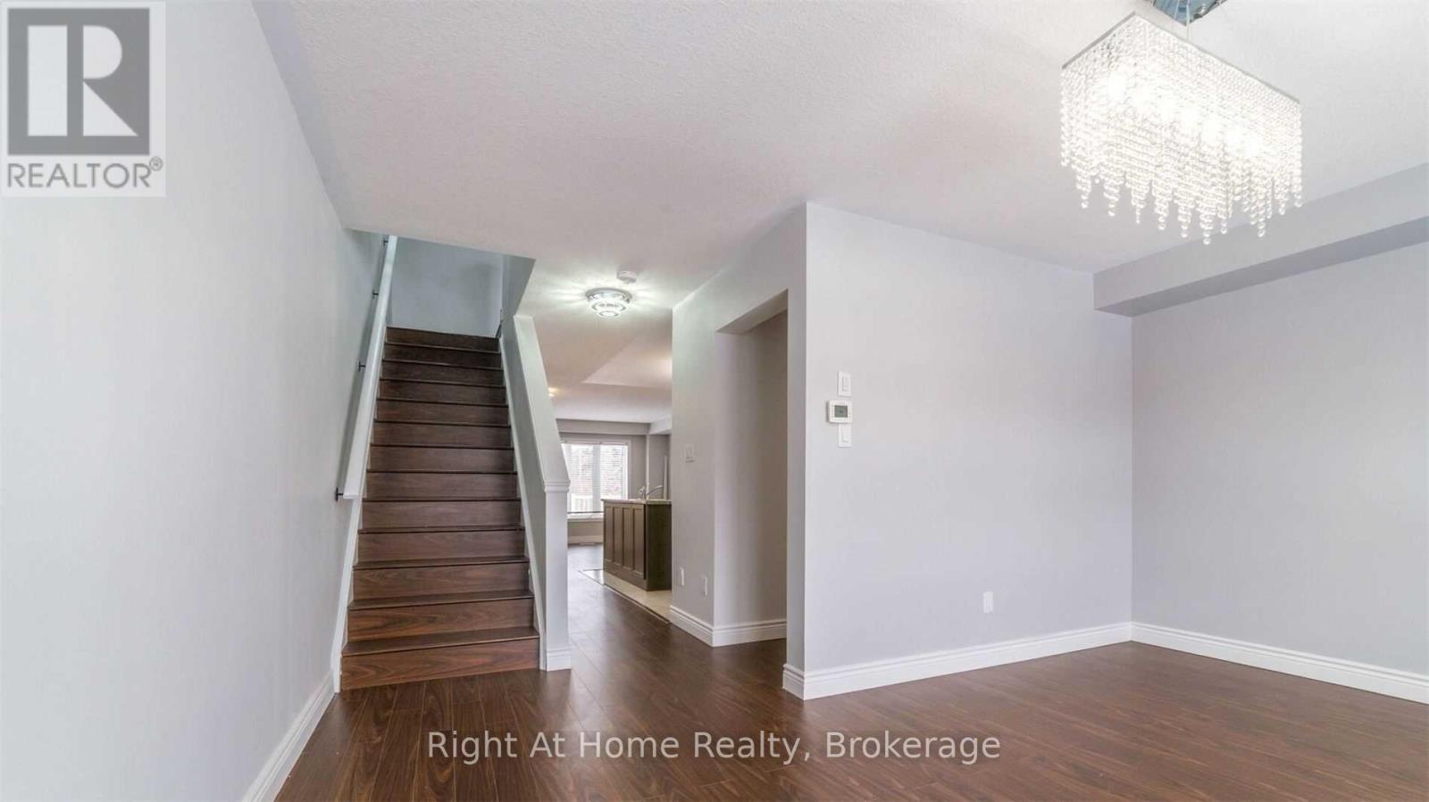 A spacious room with a chandelier and a staircase leading to another room.