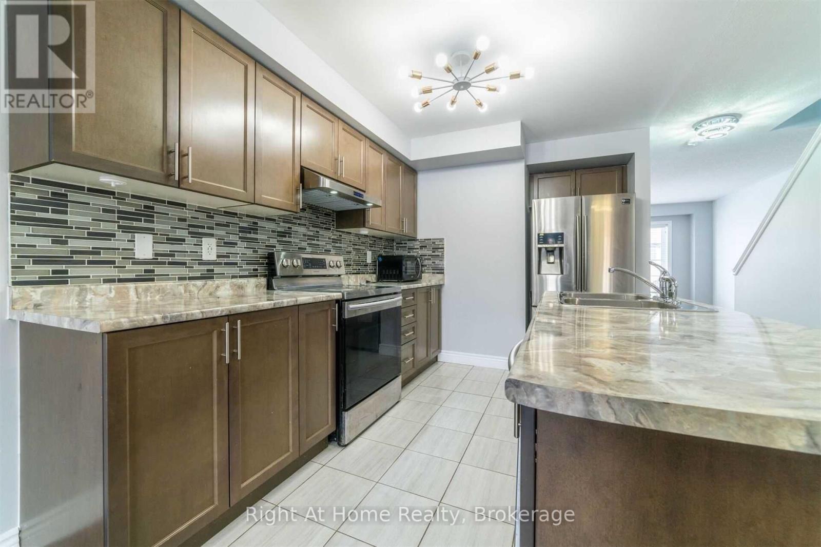 A kitchen with brown cabinets and a marble countertop.