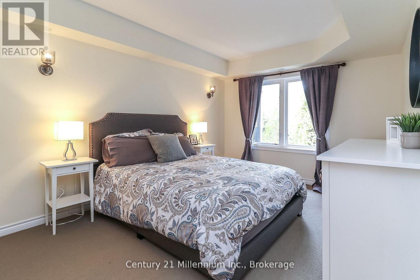 A bedroom with a bed, nightstand, and window.
