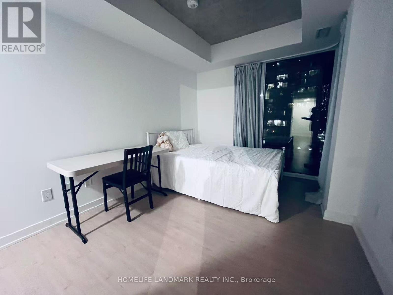A bedroom with a bed, desk, and chair.