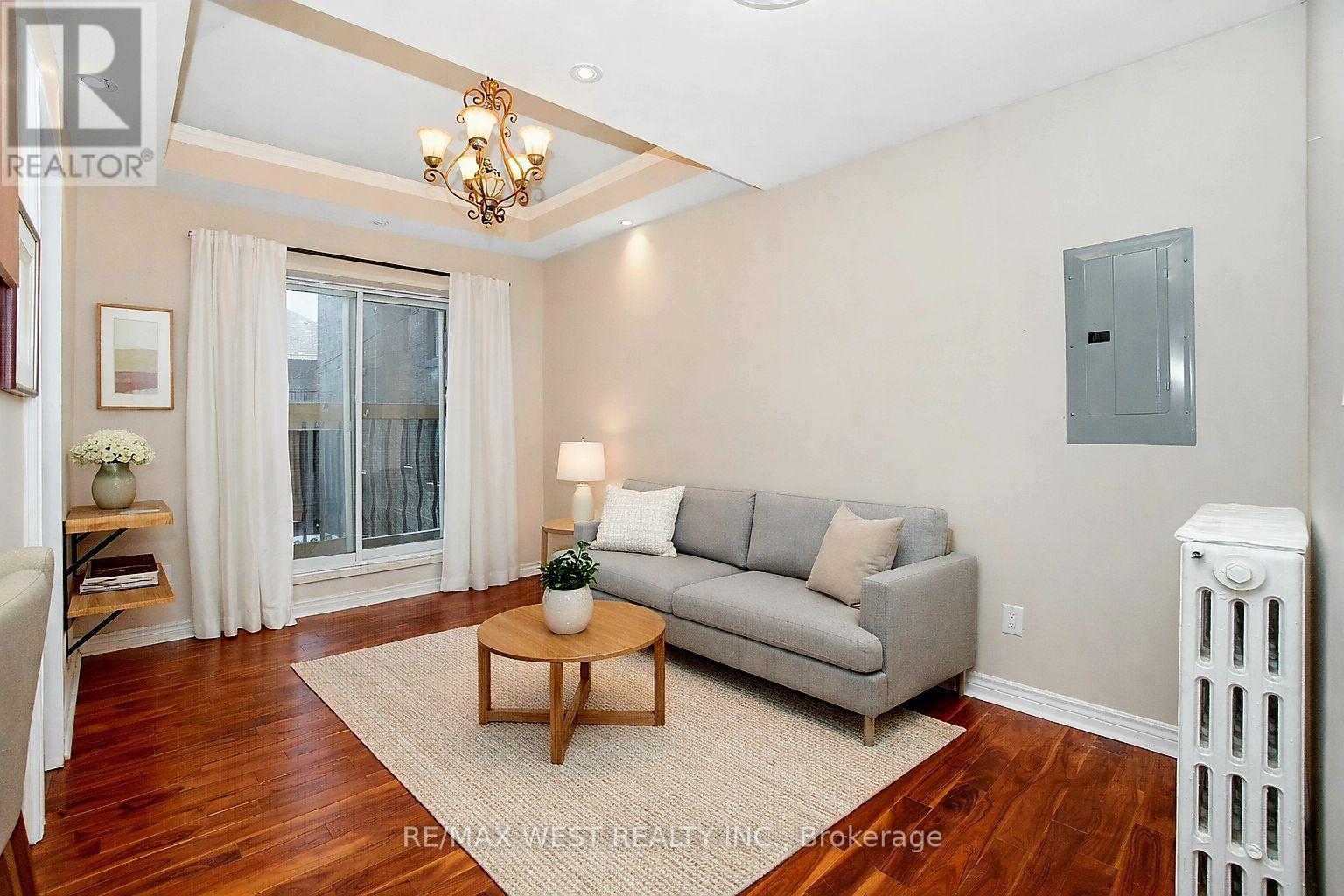 A living room with a grey couch, a wooden coffee table, and a chandelier.