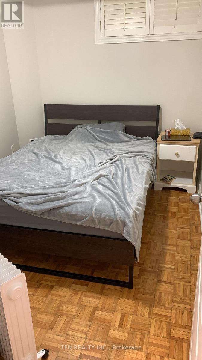 A bedroom with a bed, nightstand, and a wooden floor.