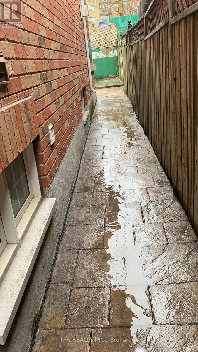 A wet brick walkway leads from a white door.