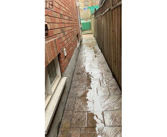 A wet brick walkway leads from a white door.