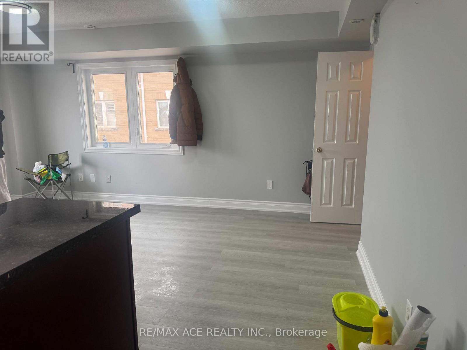 A room with a brown coat hanging on the wall and a yellow bucket on the floor.