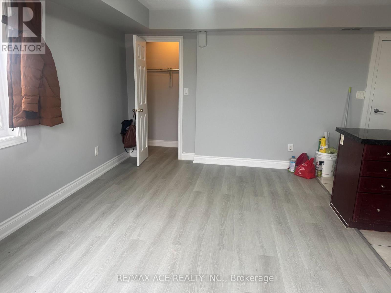 A room with a grey floor and white walls, with a doorway leading to another room.
