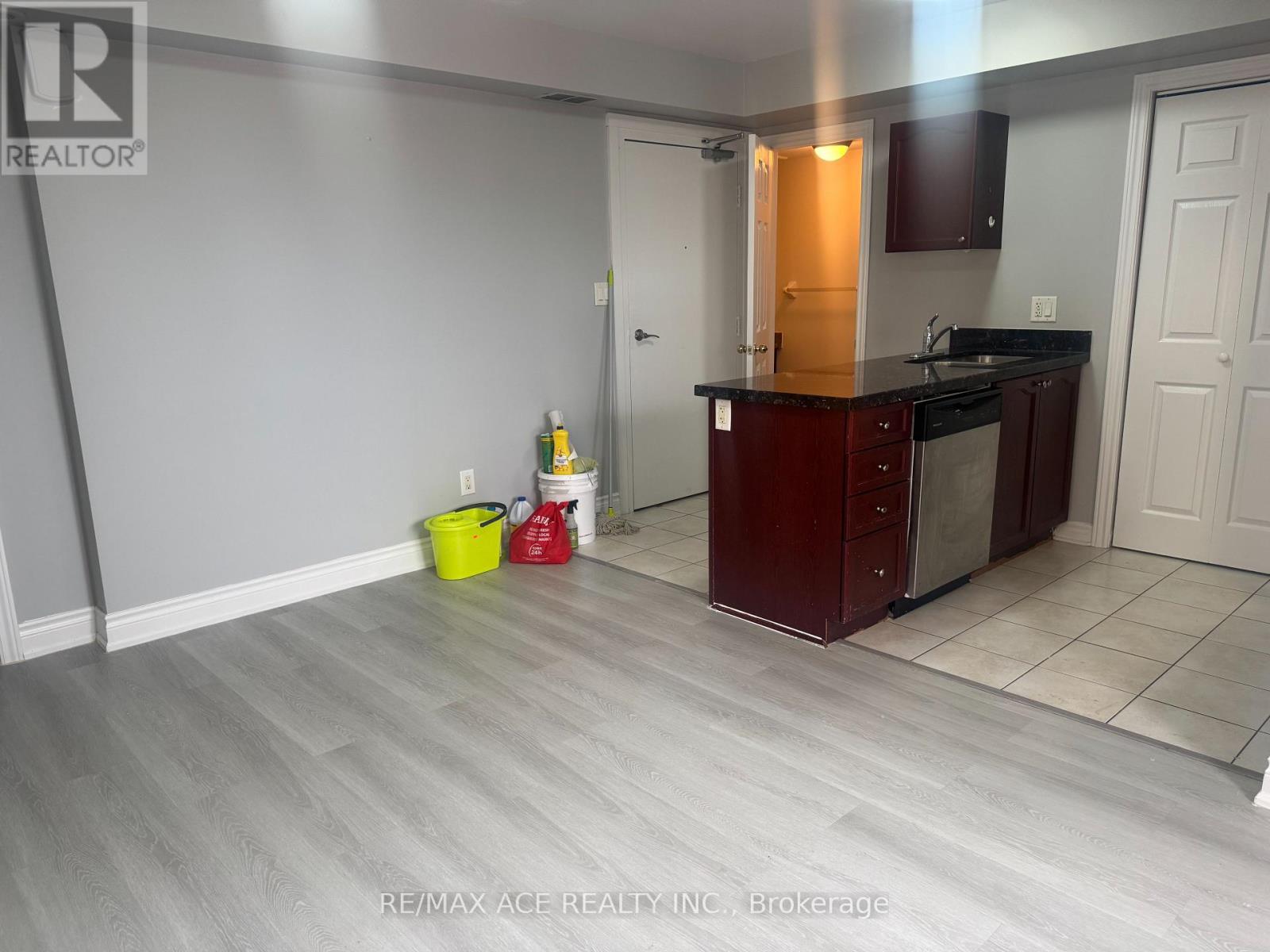 A kitchen with a red cabinet and a yellow bucket on the floor.