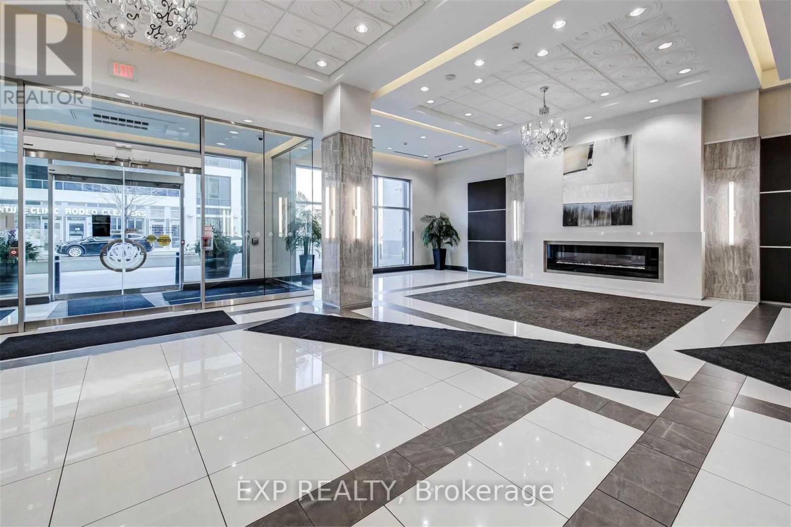 A spacious lobby with a large marble floor and a chandelier hanging from the ceiling.