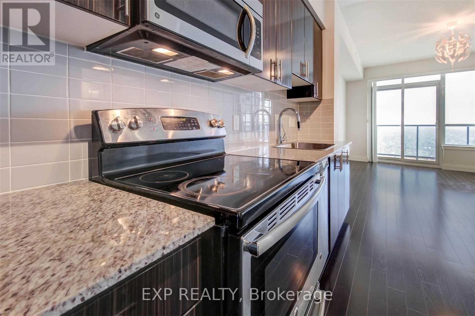 A modern kitchen with a stove top oven and a tile backsplash.