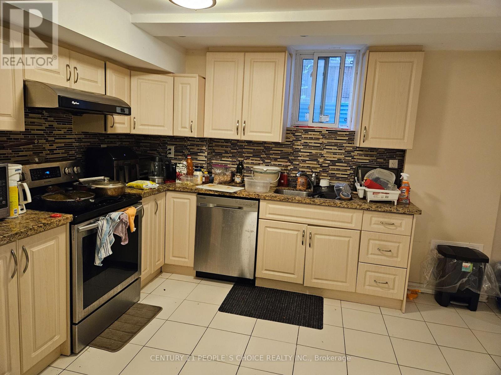 A kitchen with a black stove top oven and a black trash can.
