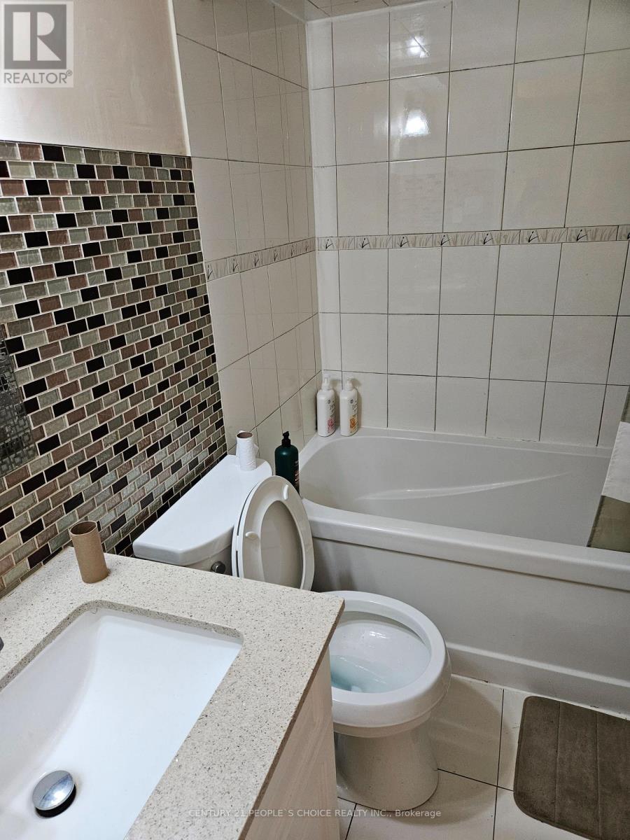 A white toilet sits next to a white sink in a bathroom.