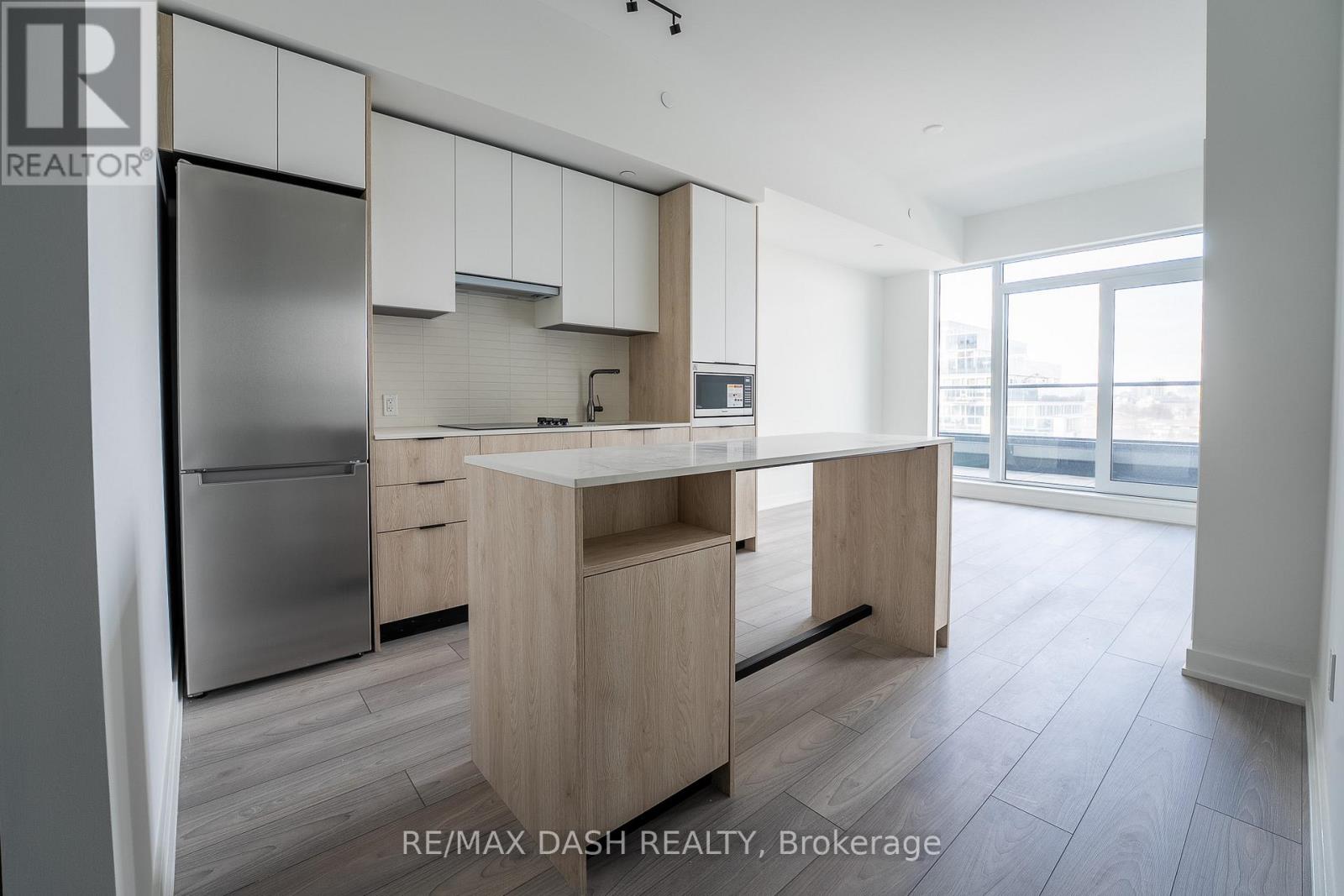 A modern kitchen with wooden cabinets and a stainless steel refrigerator.