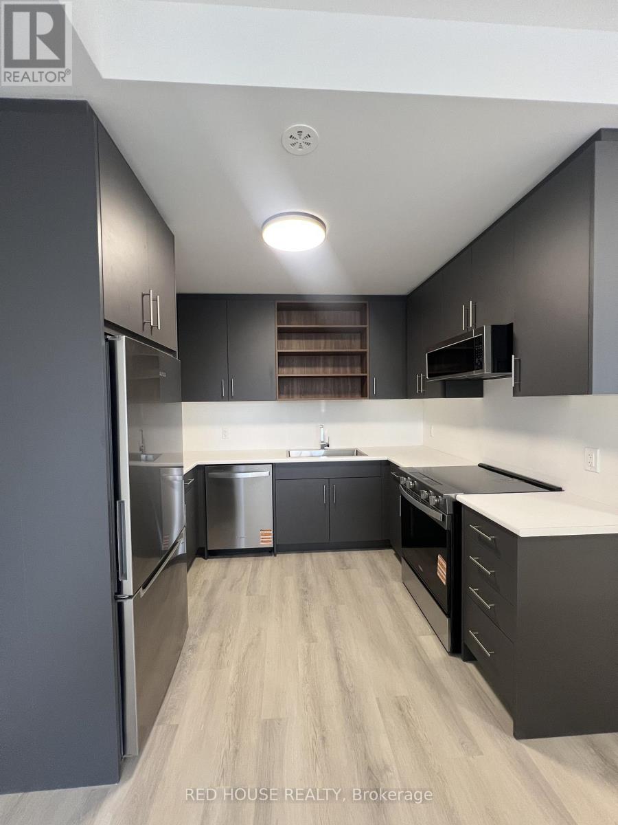 A modern kitchen with dark grey cabinets and stainless steel appliances.