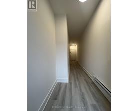 A hallway with wood flooring and white walls.