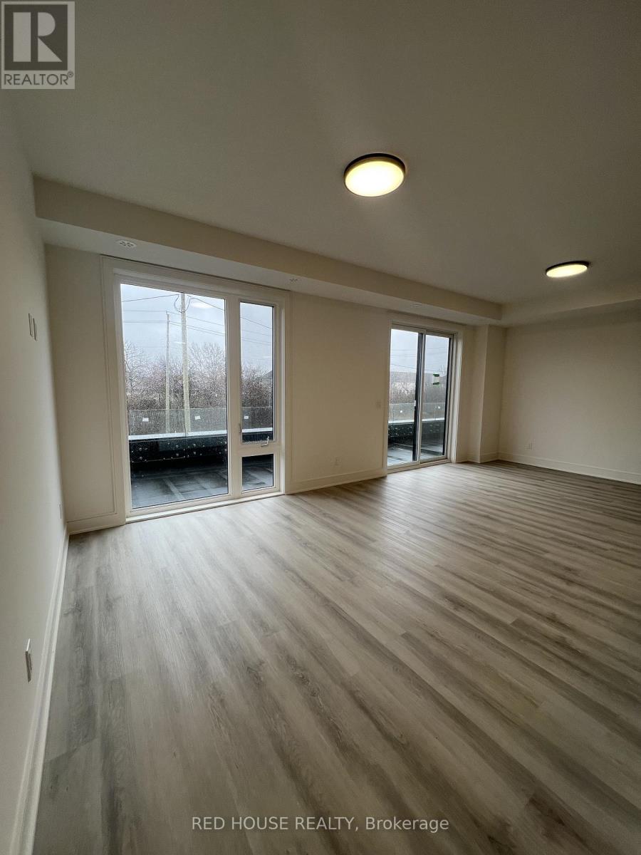 A spacious room with wooden flooring and sliding glass doors.
