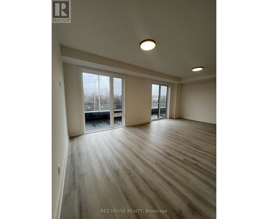 A spacious room with wooden flooring and sliding glass doors.