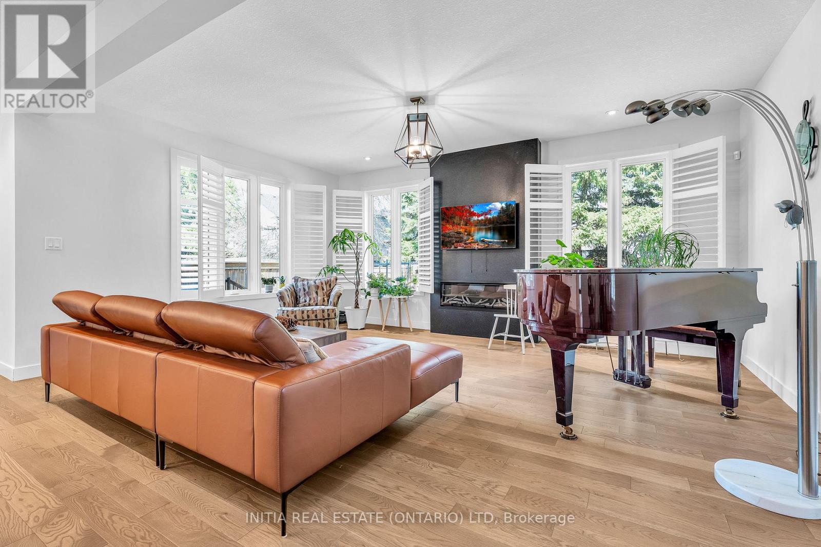 A living room with a brown leather sofa and a grand piano.