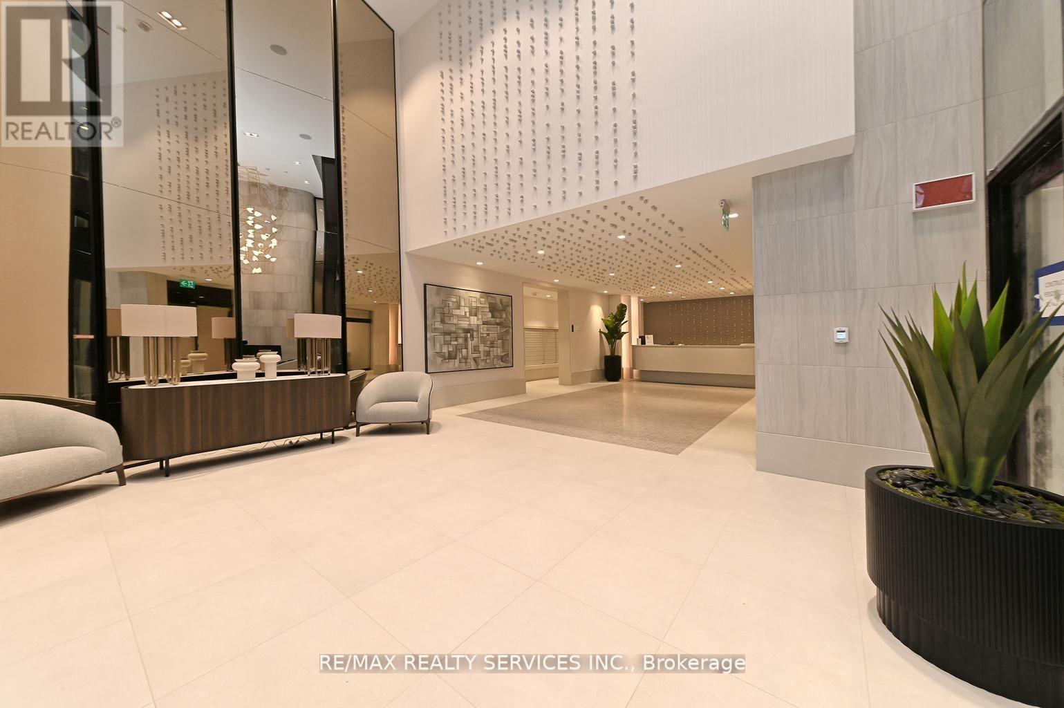 A modern office lobby with a reception desk and a plant.