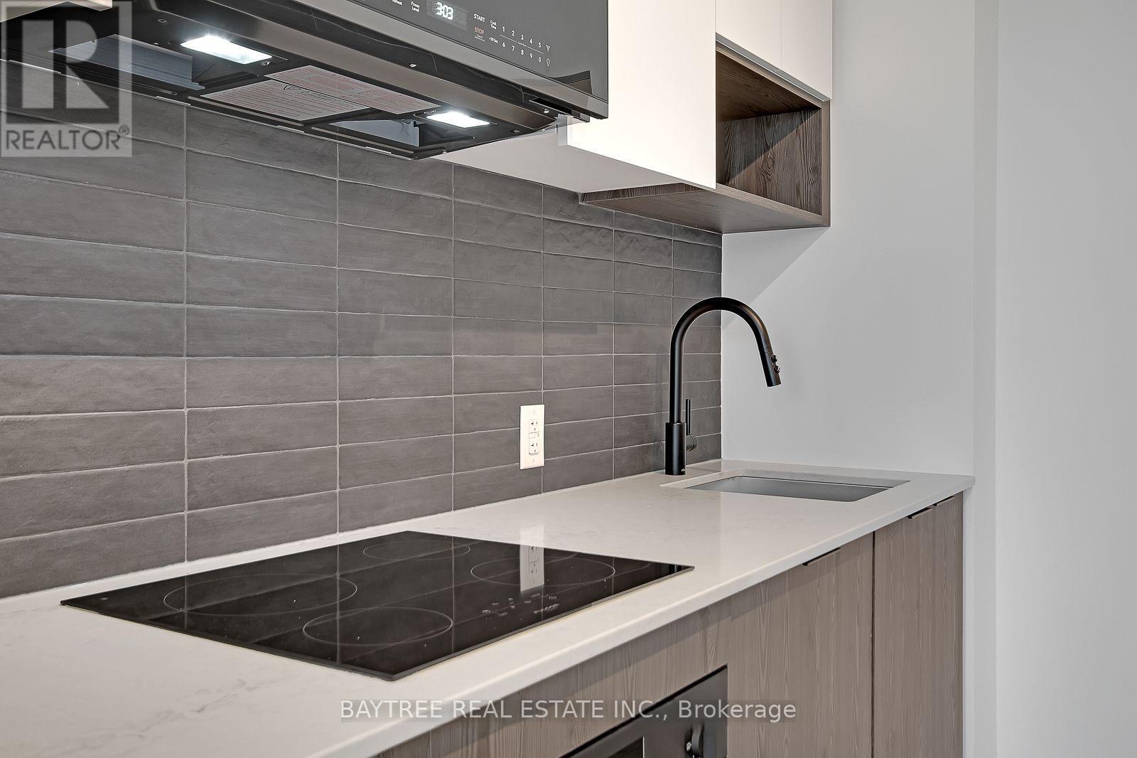 A modern kitchen with a stove top and a sink.