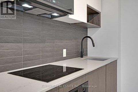 A modern kitchen with a stove top and a sink.