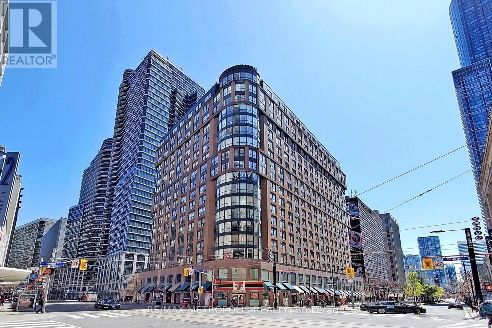 A city street with a large building in the middle and cars driving by.