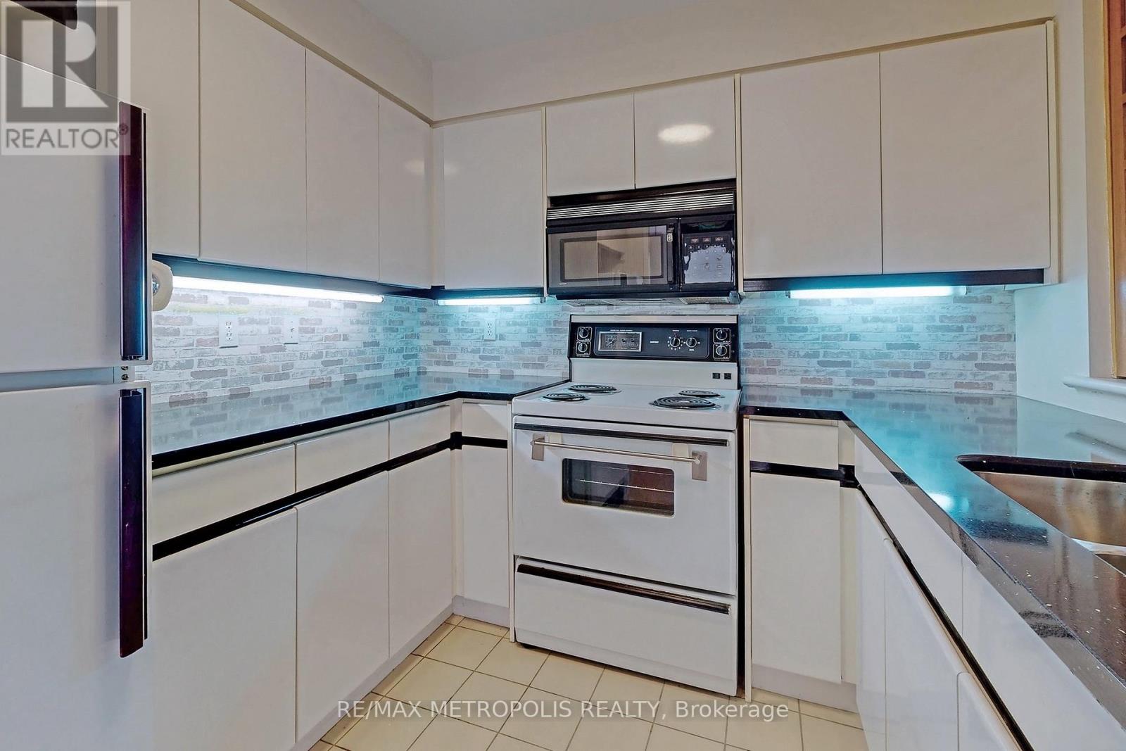 A kitchen with white cabinets and a black countertop.