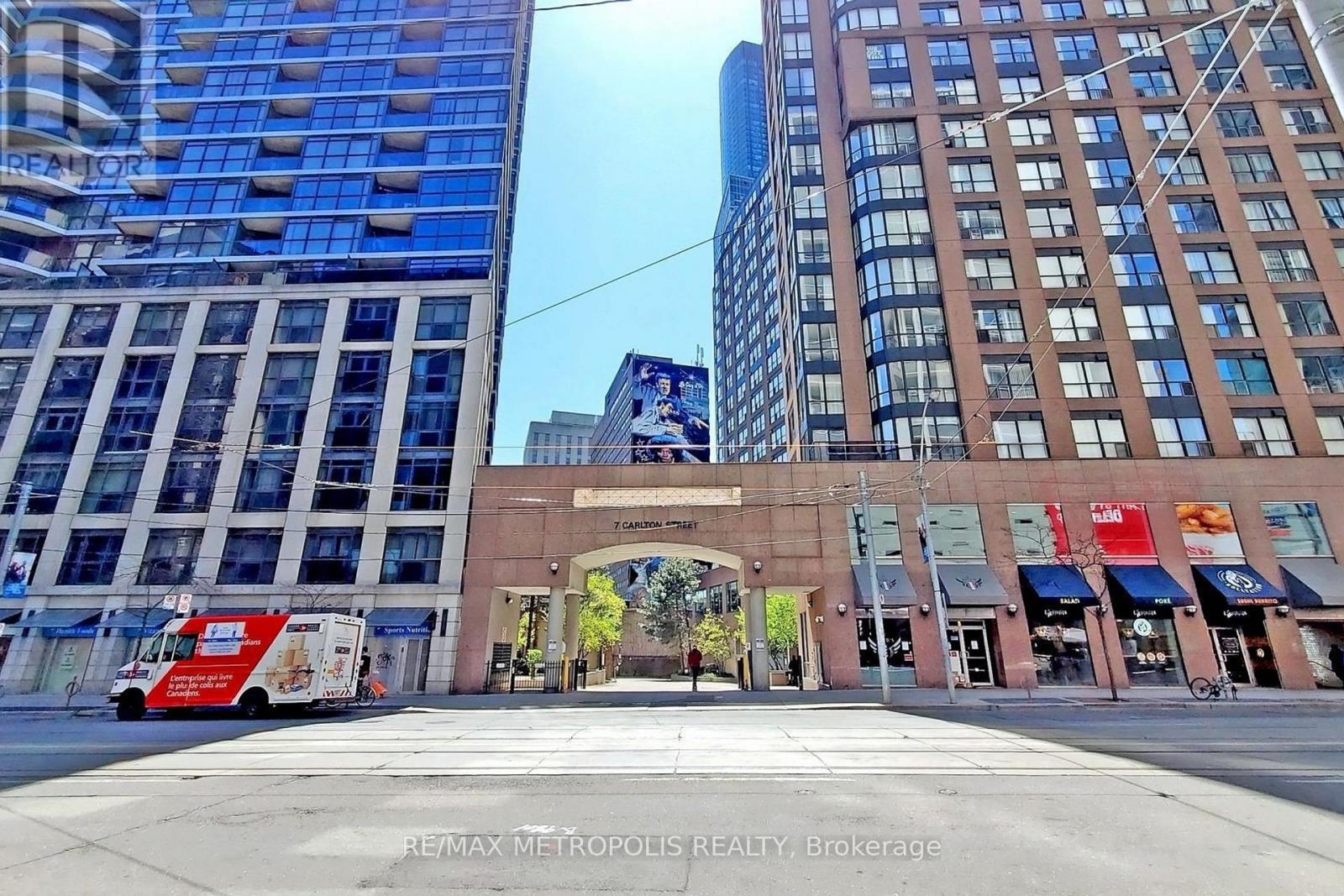 A city street with a red truck and a building with a red awning.