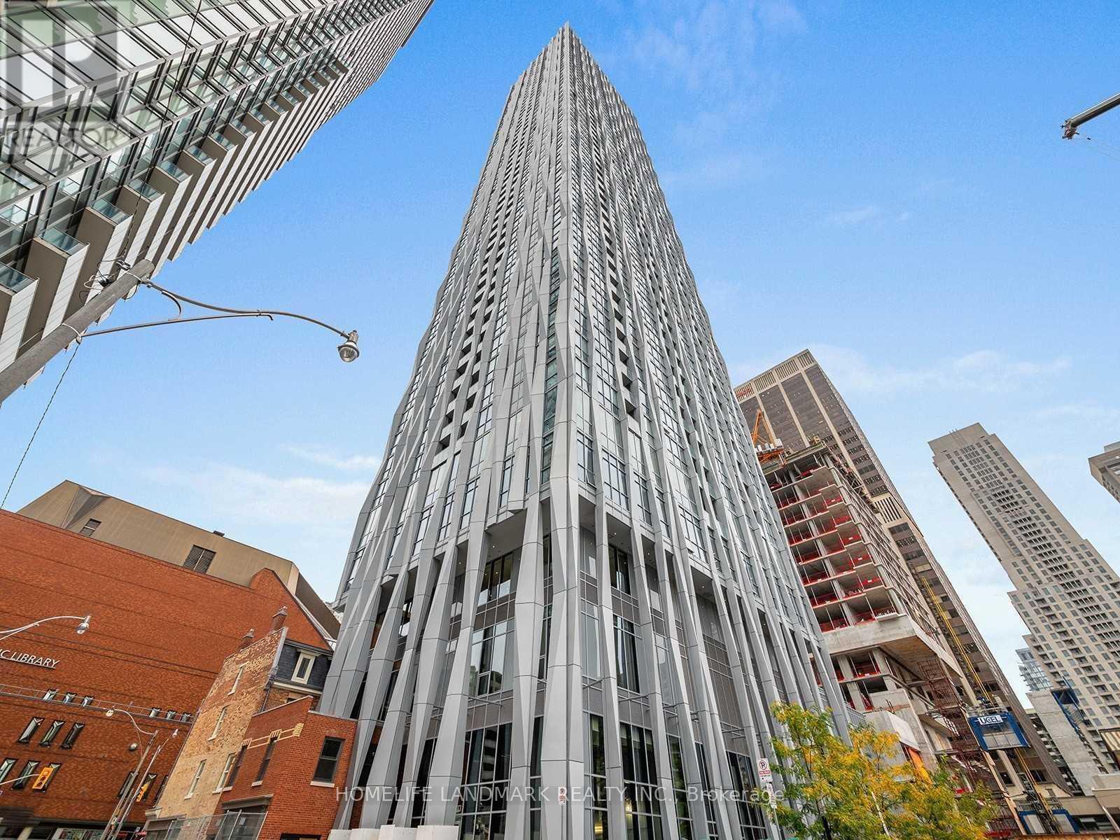 A tall, modern building with a glass facade stands in the foreground of a cityscape.
