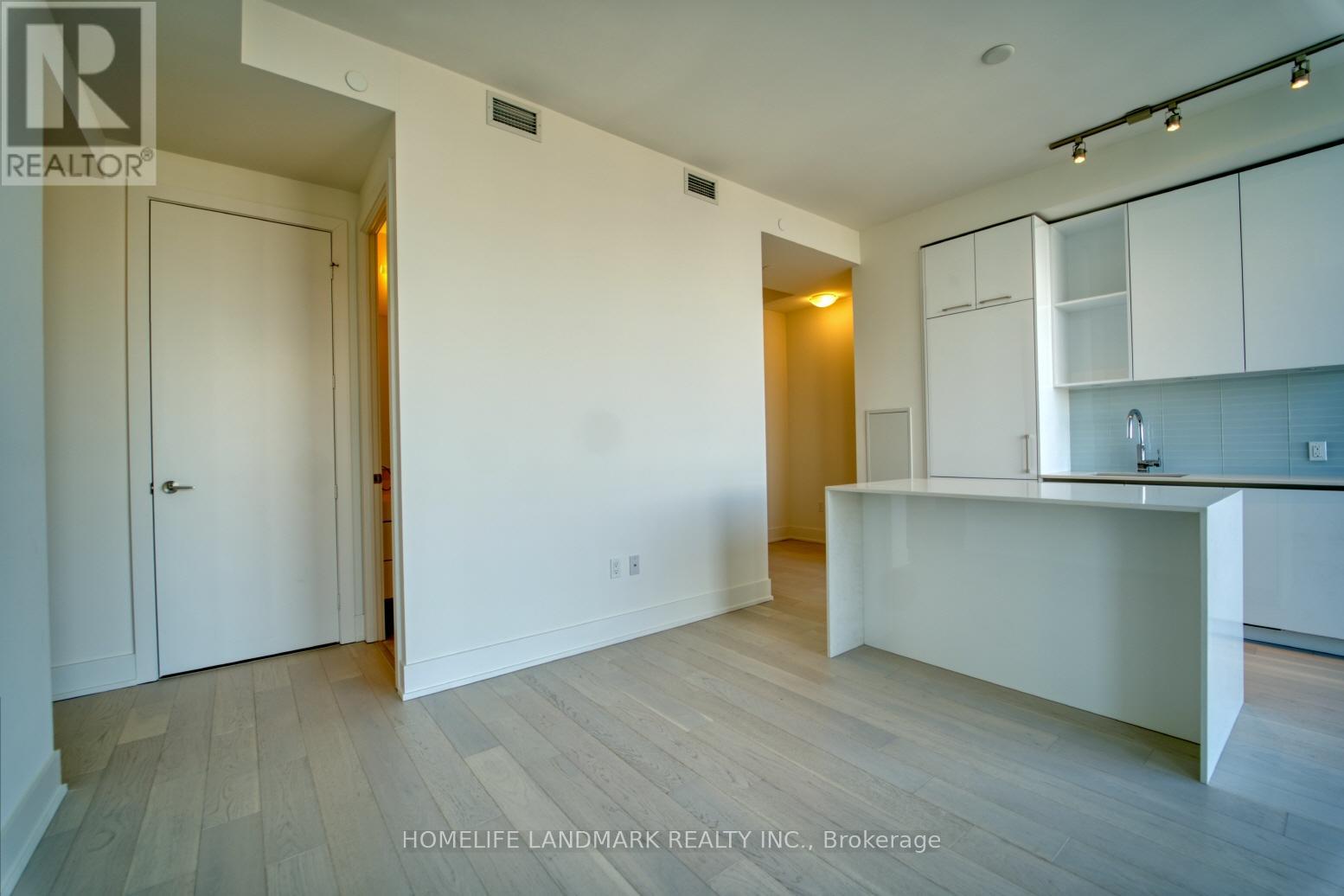 A white kitchen with a bar area and a hallway.