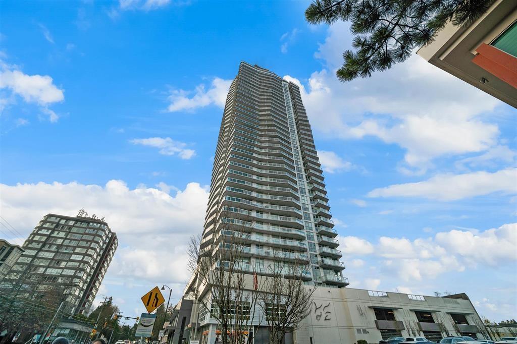 A tall building with many windows stands in front of a partly cloudy sky.