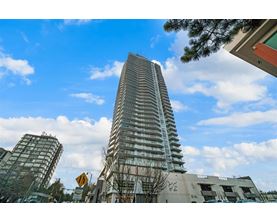 A tall building with many windows stands in front of a partly cloudy sky.