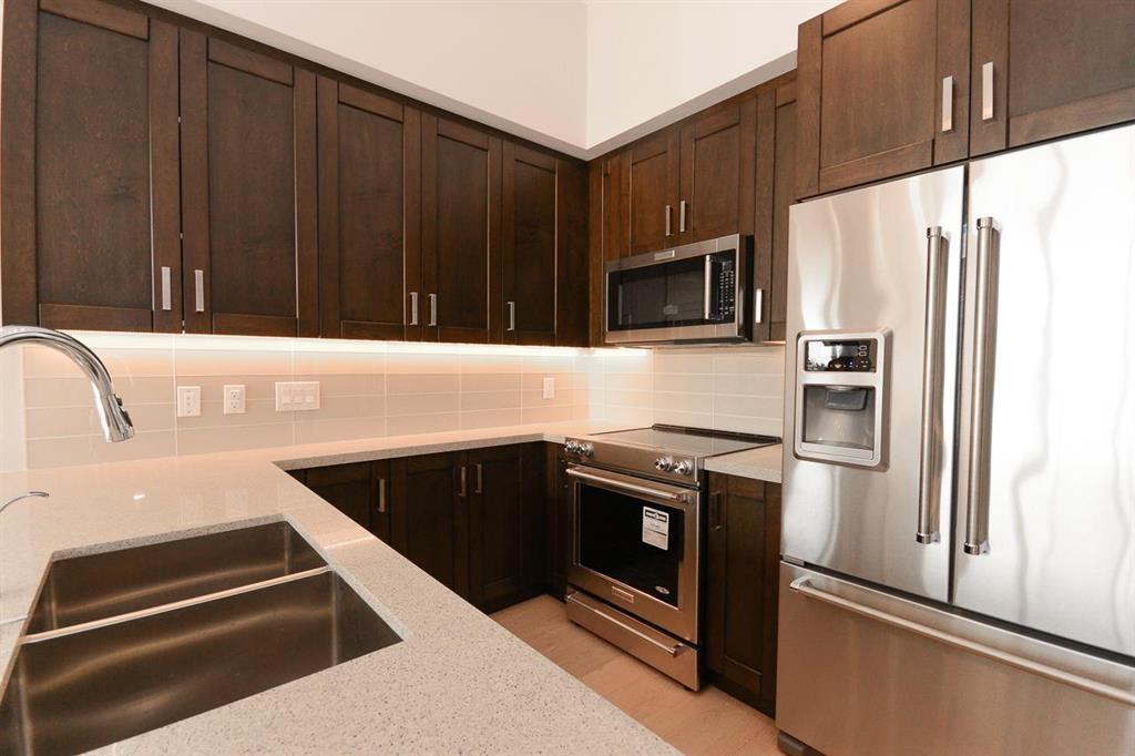 A kitchen with a stainless steel refrigerator, microwave, and oven.