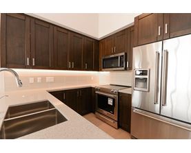 A kitchen with a stainless steel refrigerator, microwave, and oven.