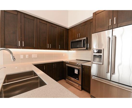 A kitchen with a stainless steel refrigerator, microwave, and oven.