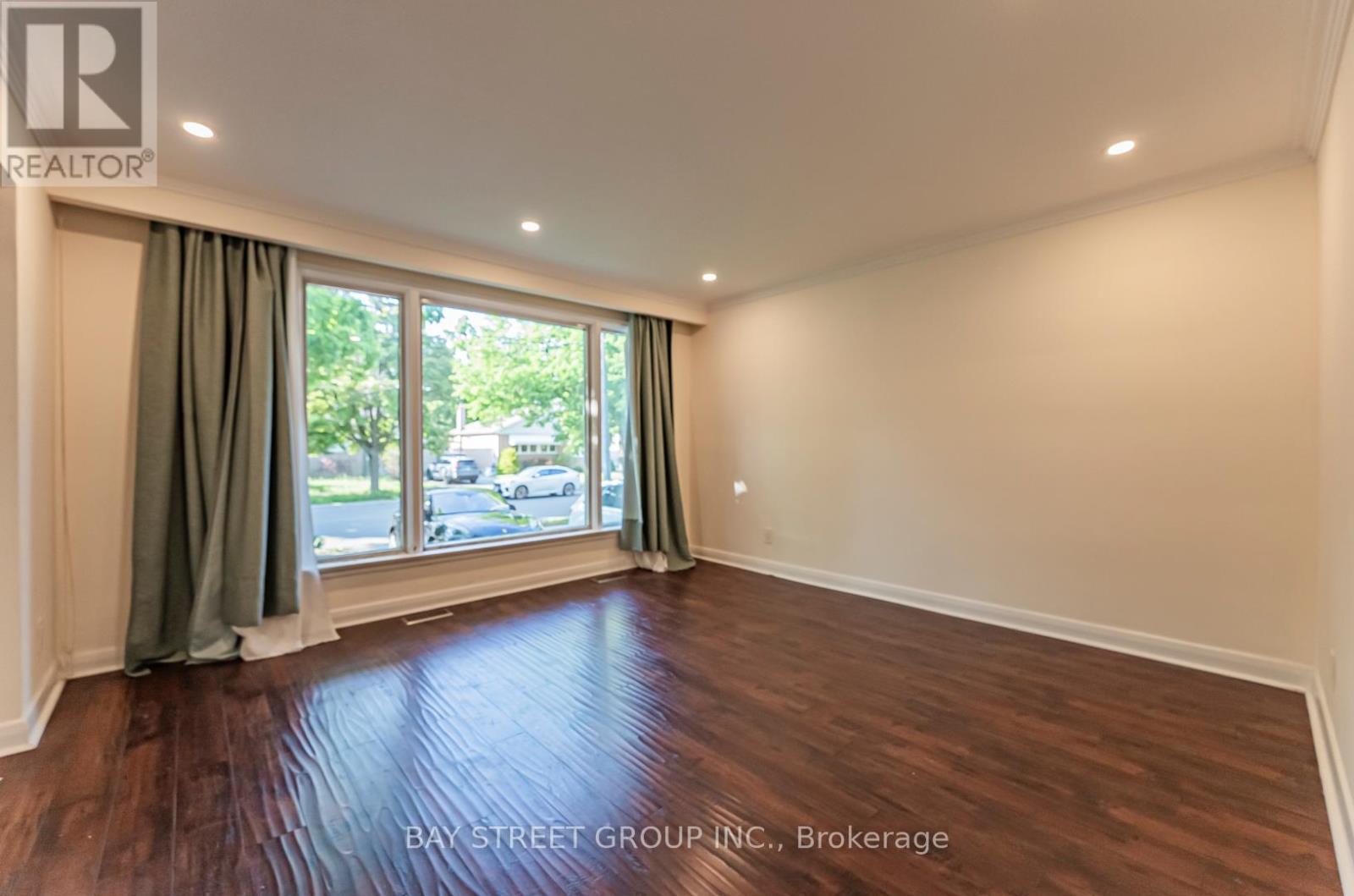 A room with a window and a wooden floor.