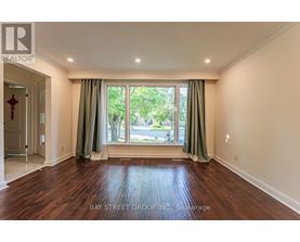 A room with wooden flooring and a large window with green curtains.