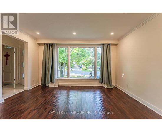 A room with wooden flooring and a large window with green curtains.