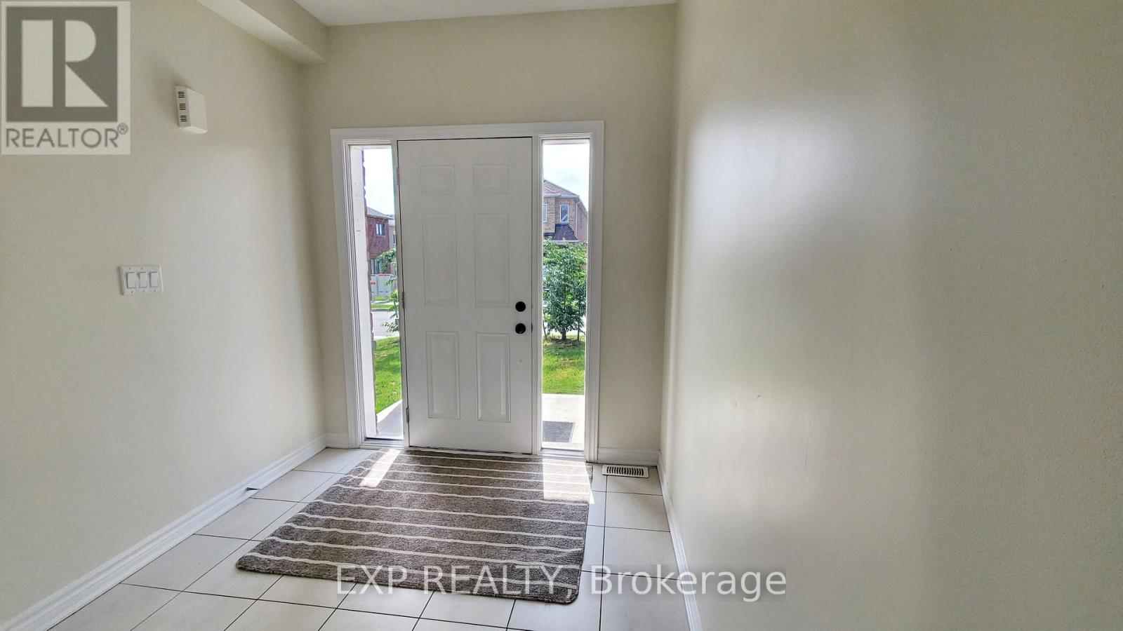 A room with a door leading outside and a rug on the floor.