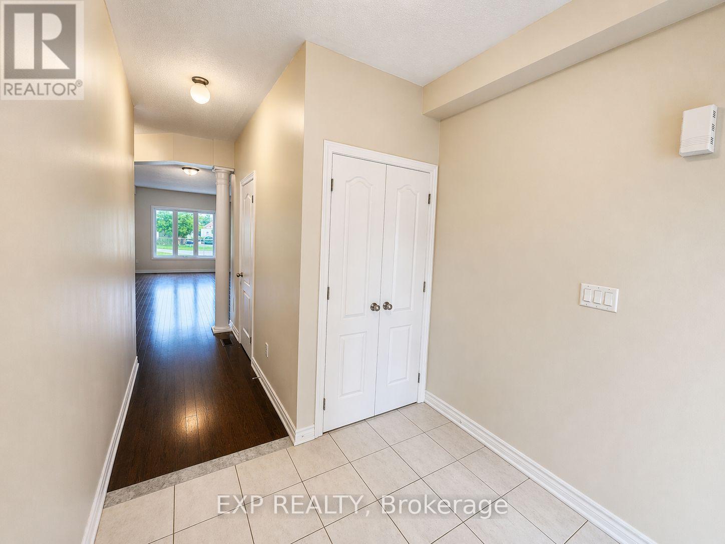 A hallway with a white door and a window with a view of trees.