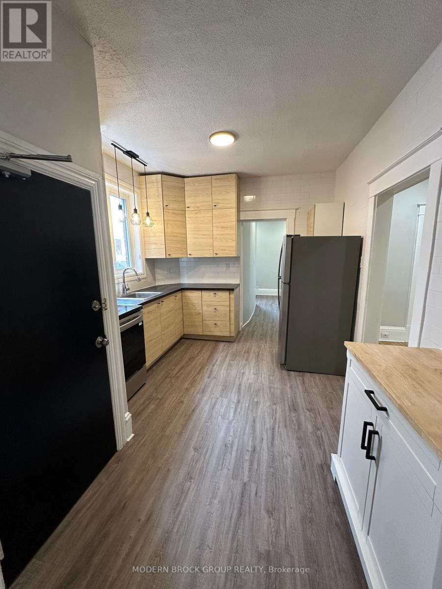 A kitchen with a black refrigerator and wooden cabinets.