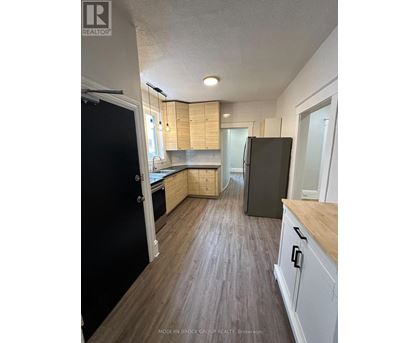 A kitchen with a black refrigerator and wooden cabinets.