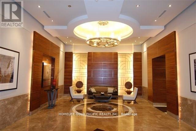 A well-lit, modern living room with a large circular chandelier and a sofa set.
