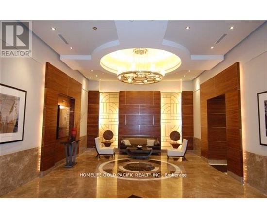 A well-lit, modern living room with a large circular chandelier and a sofa set.