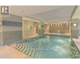 A swimming pool inside a building with a tiled wall.