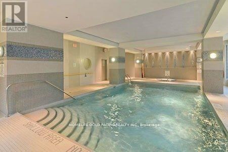 A swimming pool inside a building with a tiled wall.