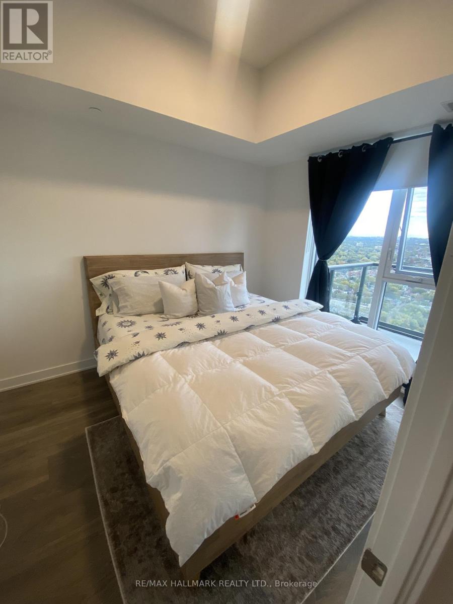 A bedroom with a large bed and a window overlooking a cityscape.