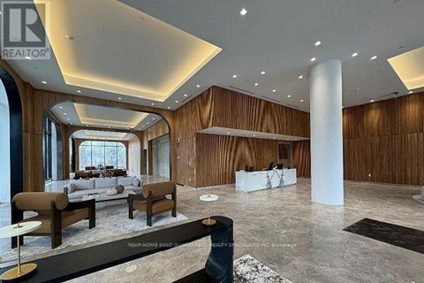 A spacious living room with a long white sofa and a black and white rug.