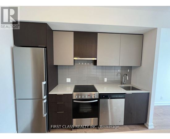 A kitchen with a refrigerator, oven, and sink.