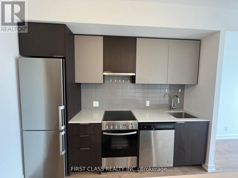 A kitchen with a refrigerator, oven, and sink.